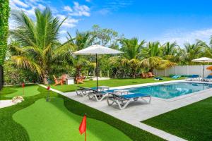 een zwembad met tafels en parasols in een tuin bij Emerald Oasis Deluxe Waterfront Gem, Heated Pool with Dock in Marathon