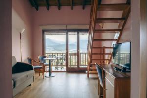 een woonkamer met een bank, een televisie en een balkon bij Cerdanya Viva Ecoestades in Prullans