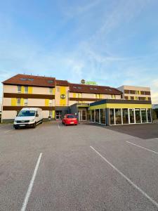 een gebouw met twee auto's geparkeerd op een parkeerplaats bij B&B HOTEL PERPIGNAN Nord Aéroport in Perpignan