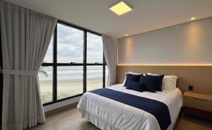 a bedroom with a bed with a view of the beach at Acqua Di Mare Pousada in Itanhaém