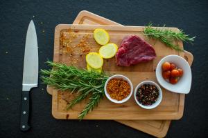 a cutting board with meat and vegetables and a knife at Hotel Osam - Adults Only in Supetar