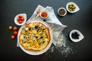 a pizza sitting on top of a table with bowls of food at Hotel Osam - Adults Only in Supetar