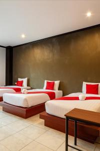 three beds in a room with red pillows on them at Nova Patong in Patong Beach