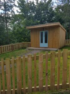 a small wooden building behind a fence at BCC Lochness Hostel pods in Bearnock +50 photos