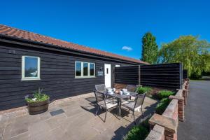 ReephamにあるPartridge Lodgeの家の前にテーブルと椅子が置かれたパティオ