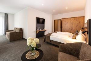 a hotel room with a bed and a couch and chair at Hotel AlpinaRos in Berchtesgaden