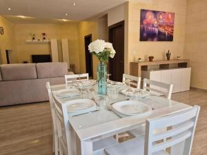 a white table with white chairs and a vase with flowers at Dar il-Wied in Għajn il-Kbira