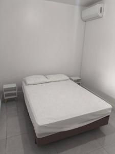 Bett in einem weißen Zimmer mit einer weißen Matratze in der Unterkunft Lindo apto 3 quartos todo novo in Torres