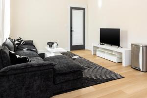 a living room with a black couch and a tv at Free parking, Free WiFi 2 bed home in Tampa