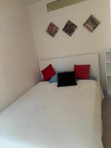 a bedroom with a white bed with red and black pillows at Bern str 140 in Ostermundigen