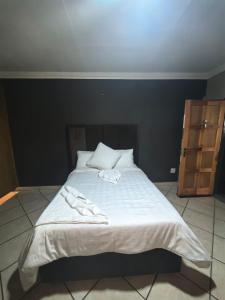 a large bed with white sheets and pillows on it at The Good Samaritan 3 in Witbank