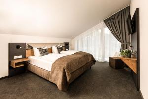 a bedroom with a large bed and a large window at Hotel AlpinaRos in Berchtesgaden