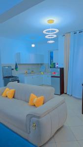 a white couch with orange pillows in a room at Staycation One and Two Bedroom apartment Mombasa in Mombasa