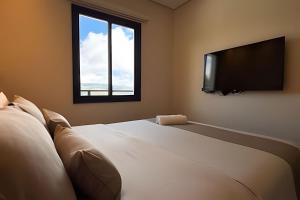 a bedroom with a large bed and a flat screen tv at Villa Cristalle - Campos do Jordão in Campos do Jordão