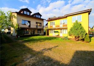 a yellow house with a yard in front of it at Nella - Pokoje gościnne in Ostrowo