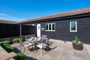 a patio with a table and chairs in front of a house at Pheasant Lodge in Reepham