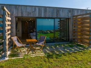 a house with two chairs and a table on a patio at Apartamentos Luscofusco Costa da Morte in Campos