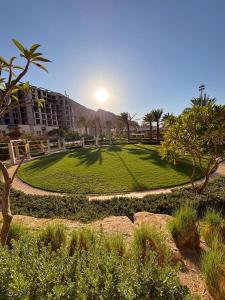 a park with a lawn with palm trees and a building at قرية الراحه مرسى زايد in Al Burj