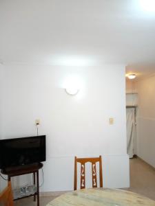 een woonkamer met een tv en een tafel en stoelen bij Depto cómodo y confortable in Olavarría