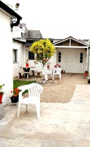 twee witte stoelen en een tafel en een boom in een tuin bij Depto cómodo y confortable in Olavarría