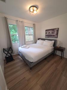 西棕榈滩Cozy 3BR WPB Cottage的卧室里有一张白色的大床和两扇窗户