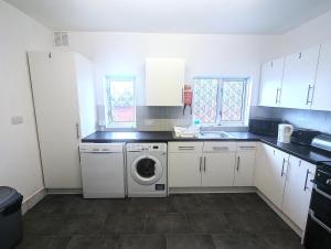 a kitchen with white cabinets and a washer and dryer at The Music Rooms! Rooms above Griffin Pub-Winter 2026 Sale! in Southampton