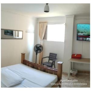 a bedroom with a bed and a chair and a window at apartaestudios luna azul rodadero in Gaira