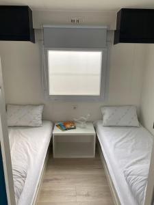 two beds in a small room with a window at Chalet D'Mar in Wenduine
