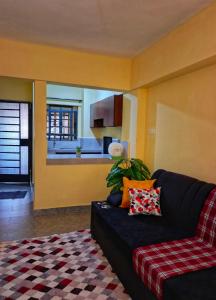 Una sala de estar con un sofá negro y una cocina. en Lin PrimeStay Suites Kisumu, en Kisumu