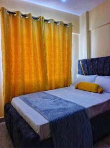 1 dormitorio con 1 cama con cortina naranja en Lin PrimeStay Suites Kisumu, en Kisumu