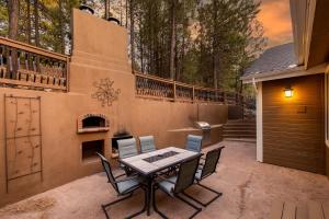 Un patio con mesa y sillas y una chimenea. en Forest Heights Mountain Views Hot Tub Heated Floors Pizza Oven, en Flagstaff