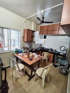 a kitchen with a wooden table and chairs at Veenus Residency - Chinchwad in Chinchwad