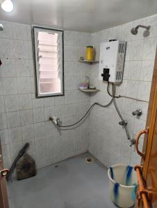 a tiled bathroom with a shower with a window at Veenus Residency - Chinchwad in Chinchwad