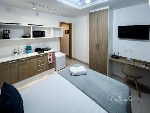 a bedroom with a bed and a desk and a tv at Studio Novíssimo Mauá 1108 in Rio de Janeiro