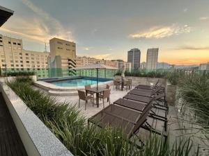 a rooftop patio with tables and chairs and a pool at Studio Novíssimo Mauá 1108 in Rio de Janeiro