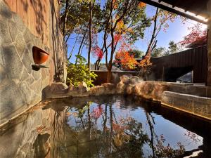 a pond in a garden with trees in the background at Ryokan YUFUMOMIJI in Yufuin