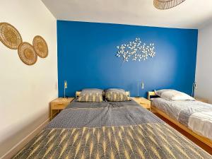 zwei Betten in einem Zimmer mit einer blauen Wand in der Unterkunft L'aube Climatisation Parking 2 chambres in Grenoble