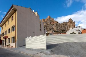 a building with a fence with a mountain in the background at Hotel Fuente El Cura in Sax