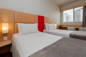Una habitación de hotel con dos camas y una ventana. en Ibis Florianopolis, en Florianópolis 127 fotos más
