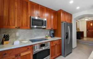 a kitchen with wooden cabinets and a stainless steel refrigerator at Kaanapali Alii 3 Bedroom Ocean View in Kaanapali