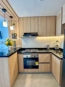 eine Küche mit Holzschränken und einem Herd mit Backofen in der Unterkunft Tu Hogar en Floridablanca - Apto de 2 Habitaciones con Aire Acondicionado in Floridablanca