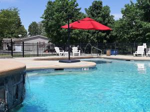 a pool with a red umbrella and chairs and a fountain at Happy Hollow Resort in Blue Eye