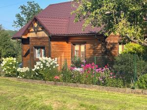 a wooden house with flowers in front of it at Agroturystka Dom w Owocowym Sadzie in Nowosielce Kozickie