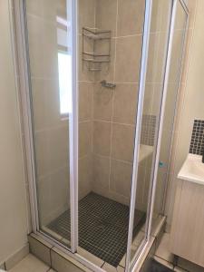 een douche met een glazen deur in een badkamer bij Rockmel Apartment in Sandton
