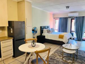 een slaapkamer met een bed, een tafel en stoelen bij Rockmel Apartment in Sandton +10 foto's