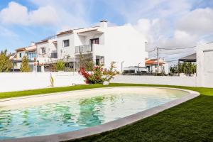 a villa with a swimming pool in front of a house at Private Room in Family Home with Pool in Sesimbra