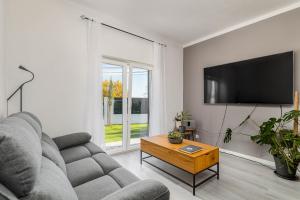 a living room with a couch and a flat screen tv at Private Room in Family Home with Pool in Sesimbra