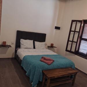 a bedroom with a bed with a green blanket and a table at Cabaña Regivan en Uspallata in Uspallata