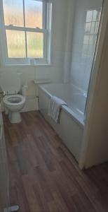 ein Badezimmer mit Badewanne und Toilette und einem Fenster in der Unterkunft Cosy Cottage-Like Apartments Axminster in Axminster