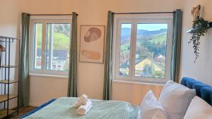 a bedroom with a bed and two large windows at Black Forest -5- I Design-Apartment I 2 Etagen I Terrasse & Balkon mit Ausblick I Boxspring I Nespresso in Oberharmersbach